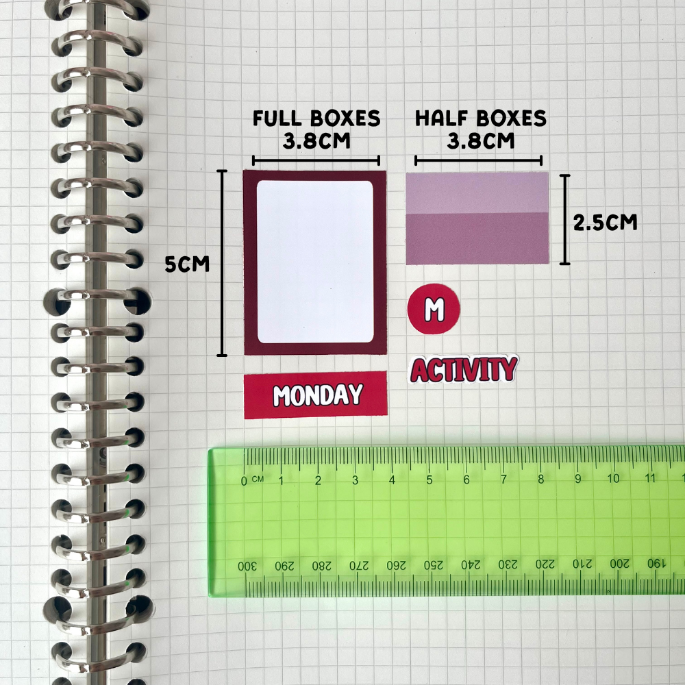 a spiral-bound notebook with various objects placed on its pages, including a ruler, a red and white label, and a blank white card.